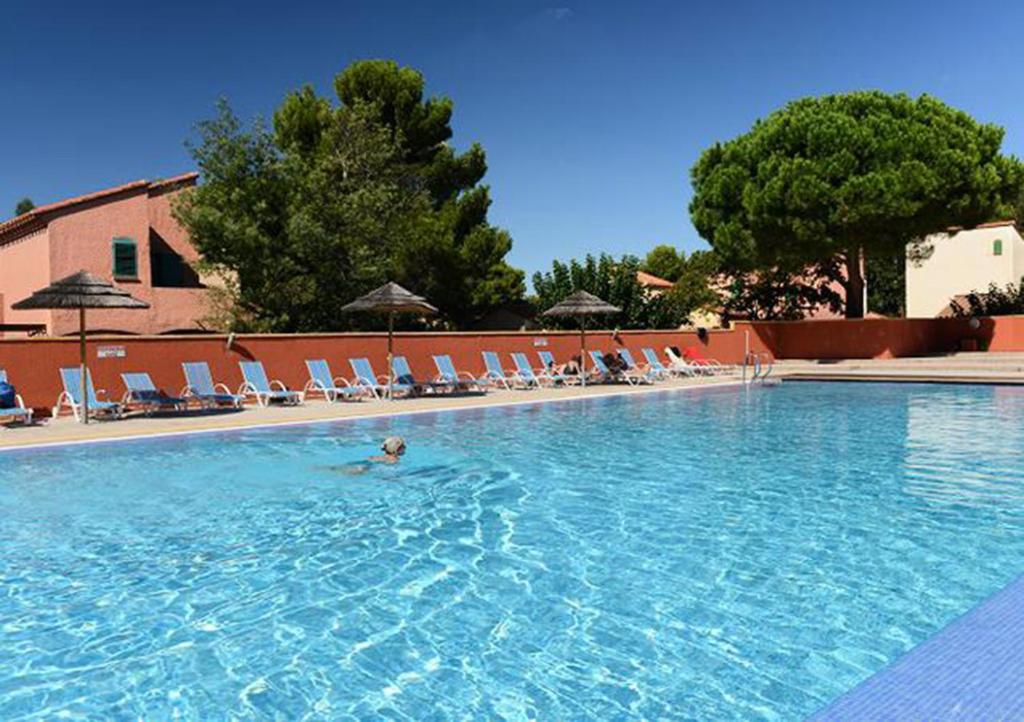 une personne se baignant dans une grande piscine avec des chaises dans l'établissement Les Albères Asclepieia Studio Ragnar, à Argelès-sur-Mer