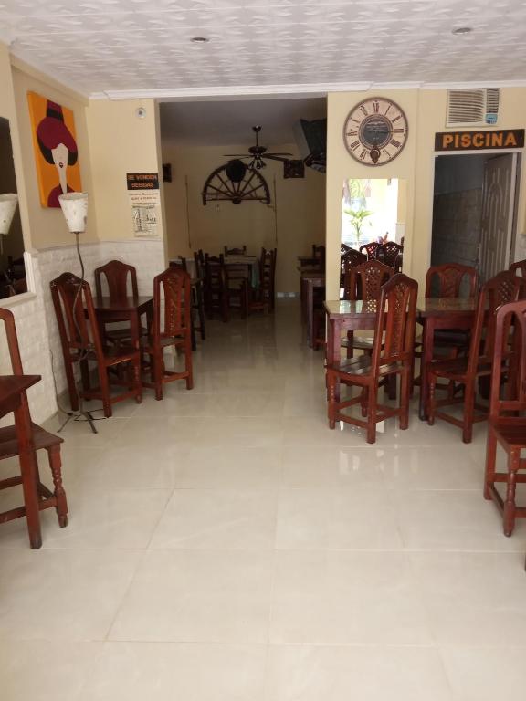a restaurant with chairs and tables and a clock on the wall at Hotel Antonia in Termas de Río Hondo