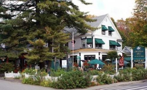 a white house with an american flag and an umbrella at Woodstock Inn, Station and Brewery in North Woodstock