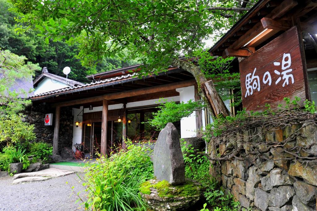a building with a stone wall in front of it at Nukumorino-yado Komanoyu in Kiso