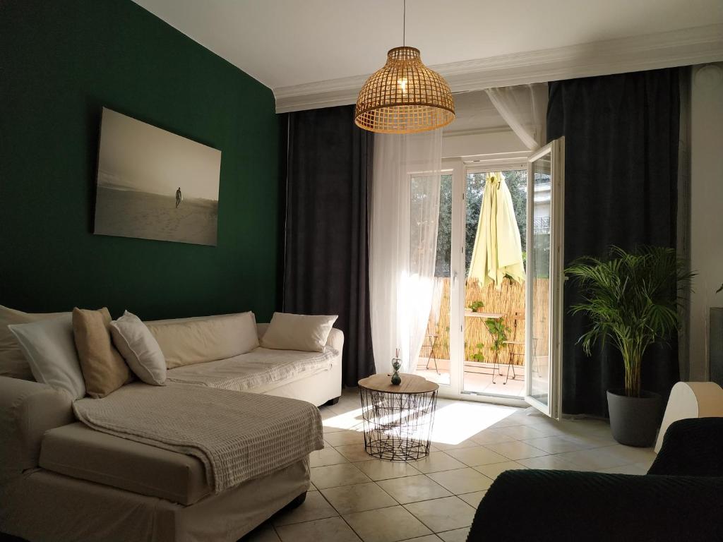 een woonkamer met een witte bank en een groene muur bij Bright Apartment steps from the Sea in Thessaloniki