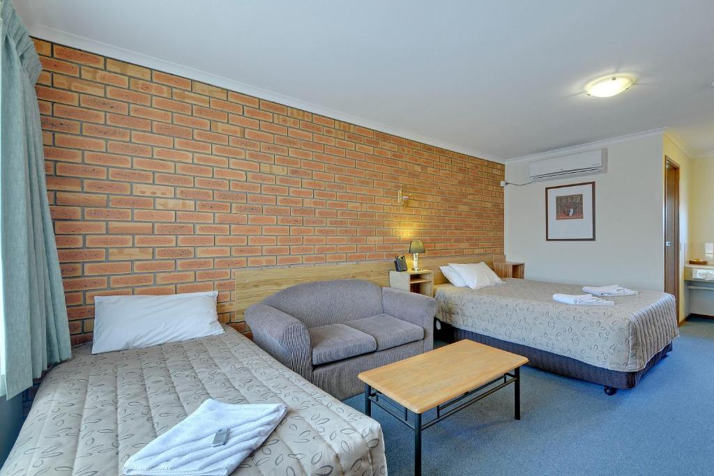 a hotel room with a bed, chair and a television at Always Welcome Motel in Morwell