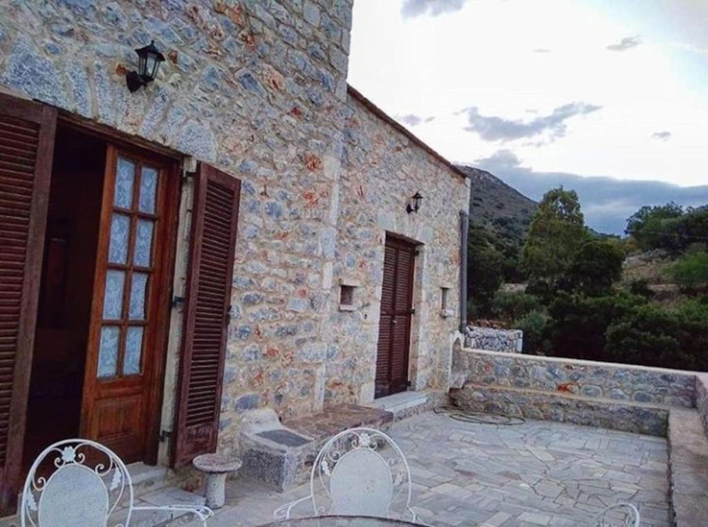 a stone house with two chairs and a door at Peace in the wildest landscape of Mani in Láyia