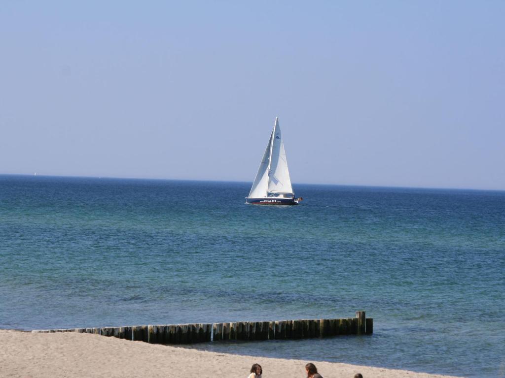 um veleiro no oceano com pessoas na praia em Allergy-friendly holiday home near the beach with lake view em Kägsdorf
