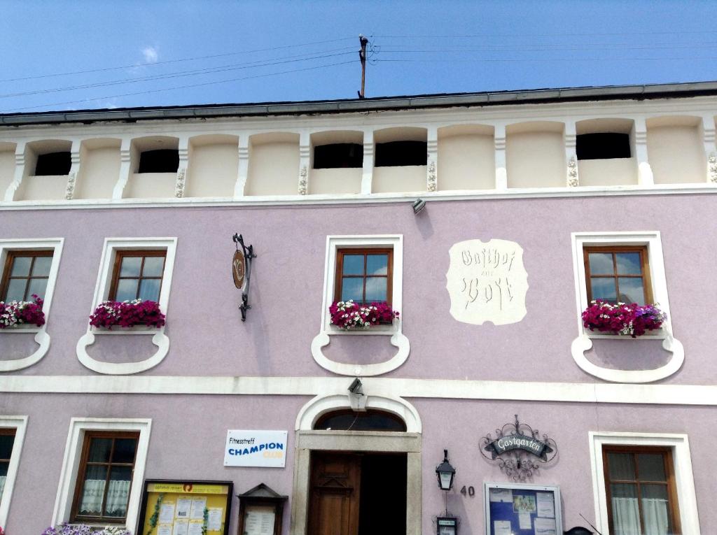 ein lila Gebäude mit Fenstern und Blumen darauf in der Unterkunft Frühstückspension zur Post Reisinger KG St Oswald in Sankt Oswald bei Freistadt