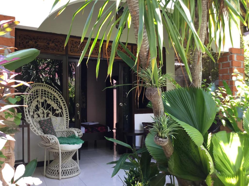 a porch with two chairs and palm trees at Gili Nyepi in Gili Trawangan
