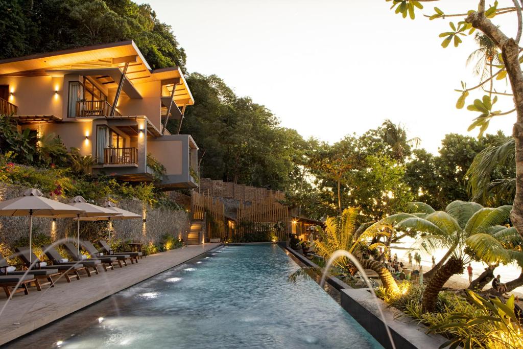 an infinity pool in front of a building with a resort at Maremegmeg Beach Club in El Nido