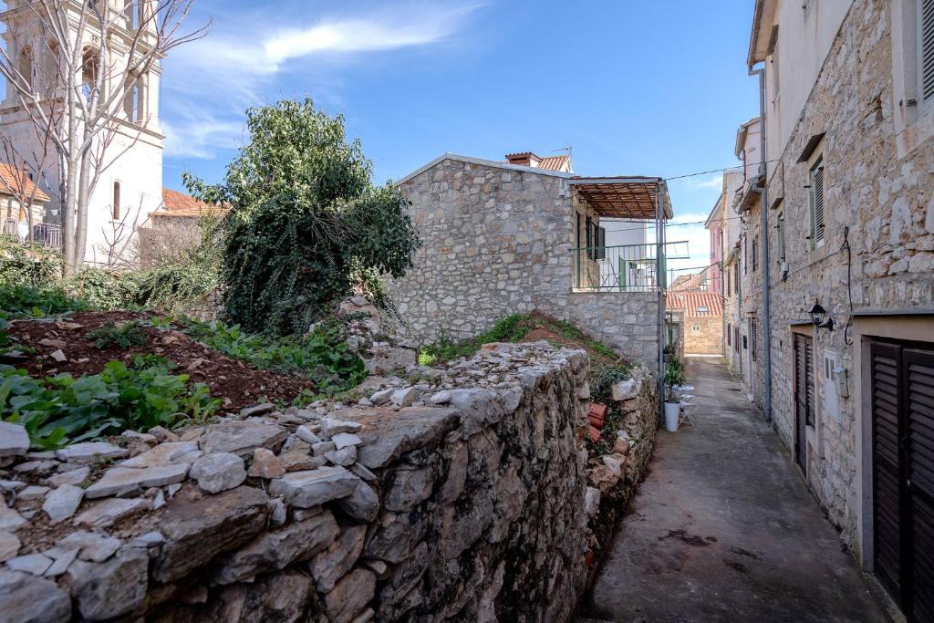 eine Gasse mit einer Steinmauer neben einem Gebäude in der Unterkunft Apartments Lotti in Stari Grad