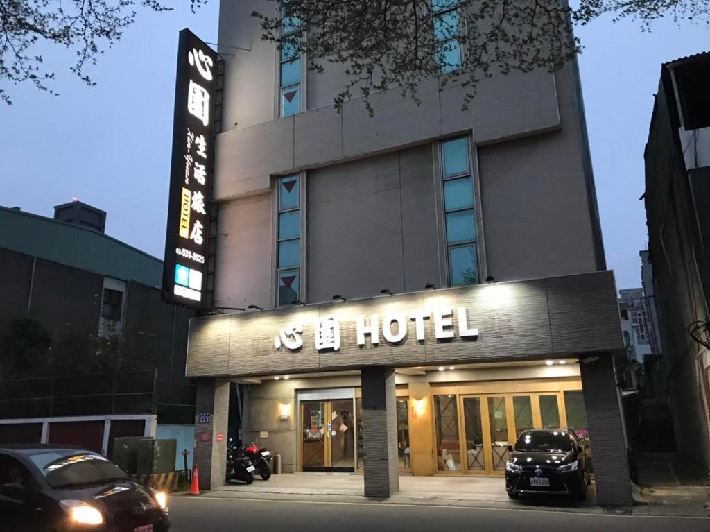 un hotel con un coche aparcado delante de él en 心園生活旅店 Xin Yuan Hotel, en Hsinchu City