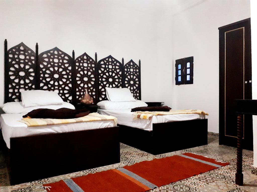 um quarto com 2 camas e lençóis brancos em Arabian Nights Pyramids Guesthouse no Cairo