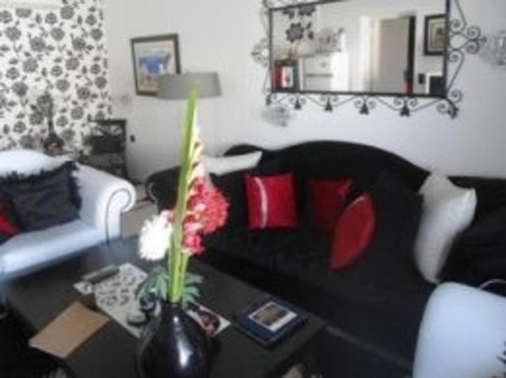 a living room with a black couch and a table with flowers at Luxury Living Apartment in Hammamet