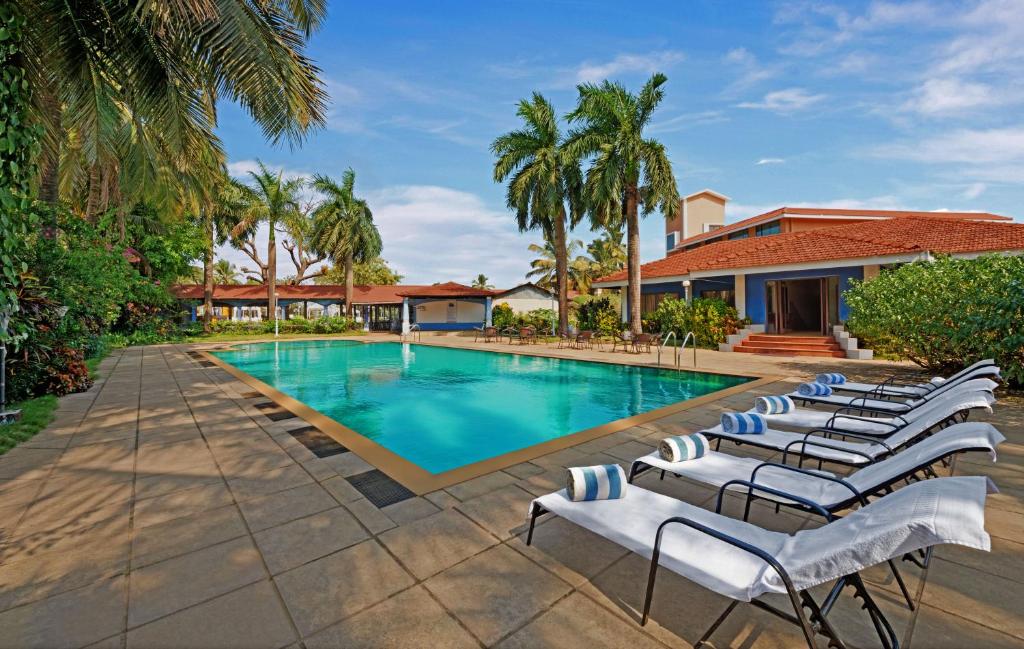 a swimming pool with lounge chairs in front of a house at The Fern Kesarval Hotel & Spa, Verna Plateau - Goa in Verna