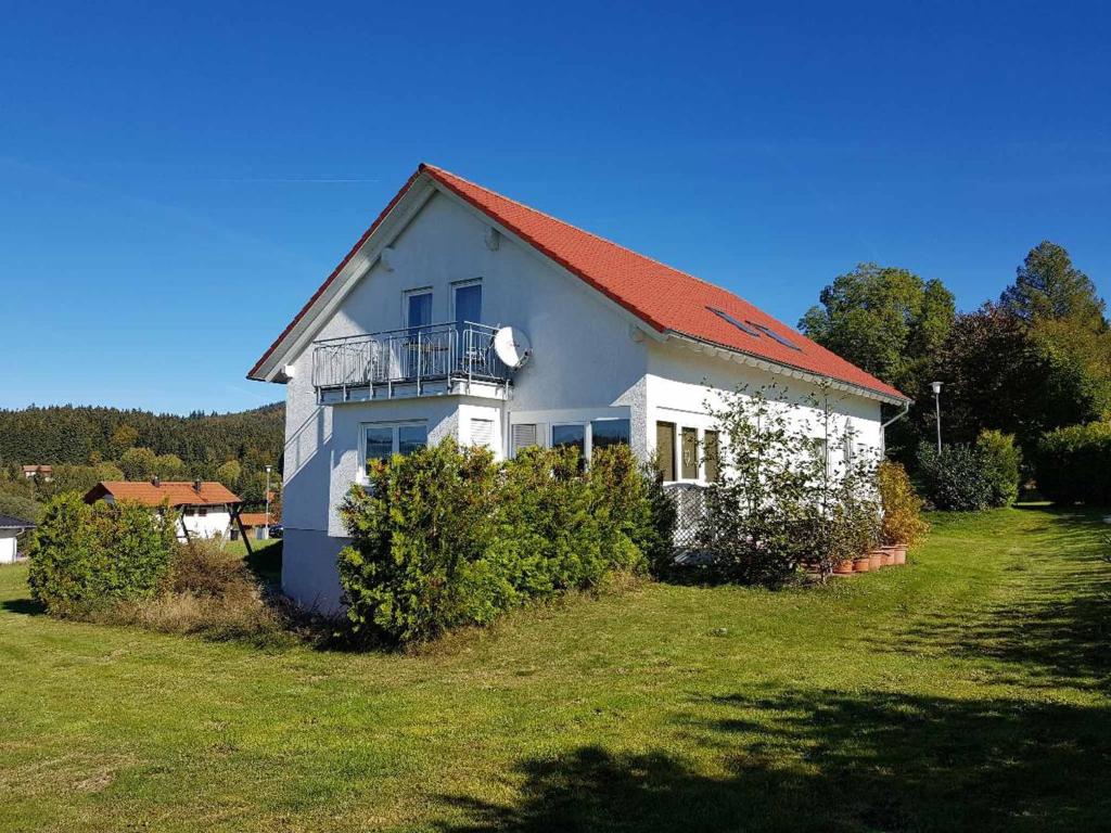 a white house with a red roof on a green field at Haus Gerrie in Mauth