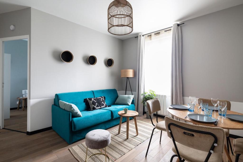 een woonkamer met een blauwe bank en een tafel bij Joli T2, gare, intra-muros & plage à proximité in Saint-Malo