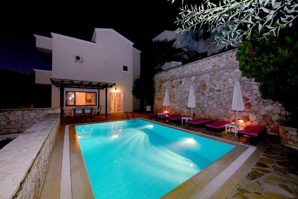 a swimming pool in front of a building at night at Villa Gwendoline in Kalkan