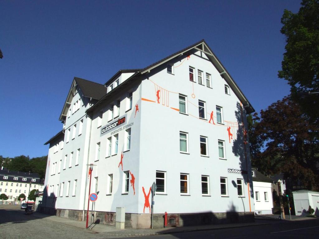 un gran edificio blanco con banderas rojas. en Outdoor Inn Sporthotel Steinach, en Steinach