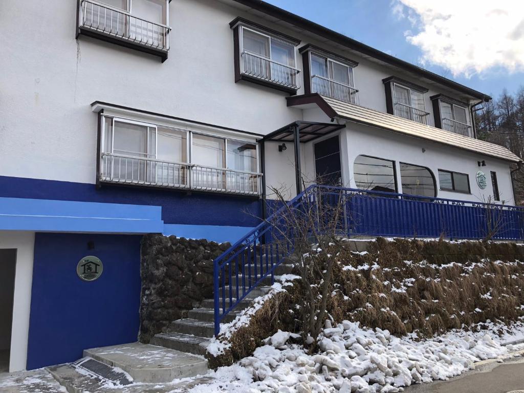 a blue and white house with snow in front of it at Oyado Zen in Kusatsu