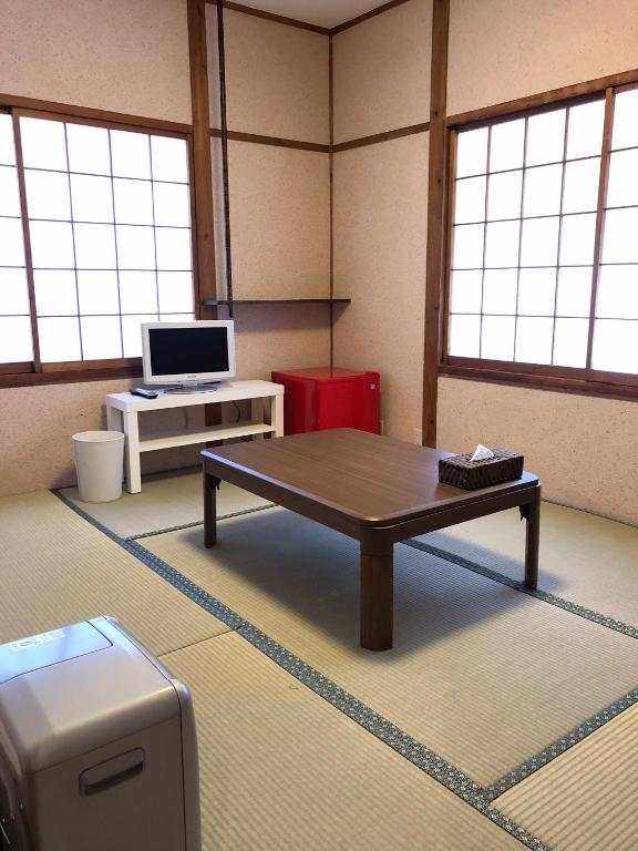 a room with a table and a desk with a computer at Oyado Zen in Kusatsu