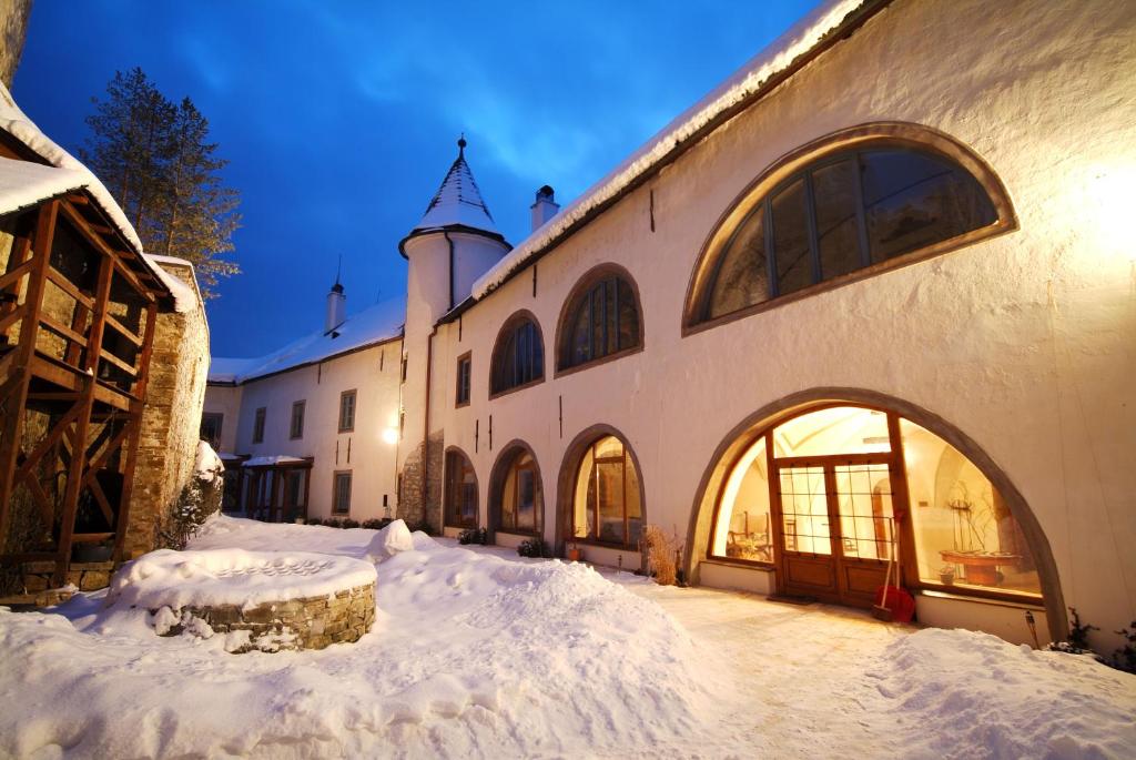 a building with snow on the ground in front of it at Chateau GrandCastle in Liptovský Hrádok