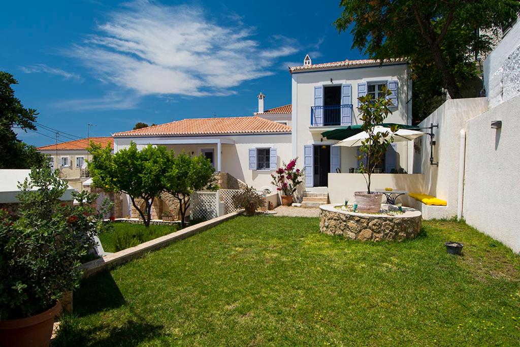 una casa blanca con un patio con césped verde en VILLA AELIA in Spetses - charm & convenience, 2min beach, en Spetses