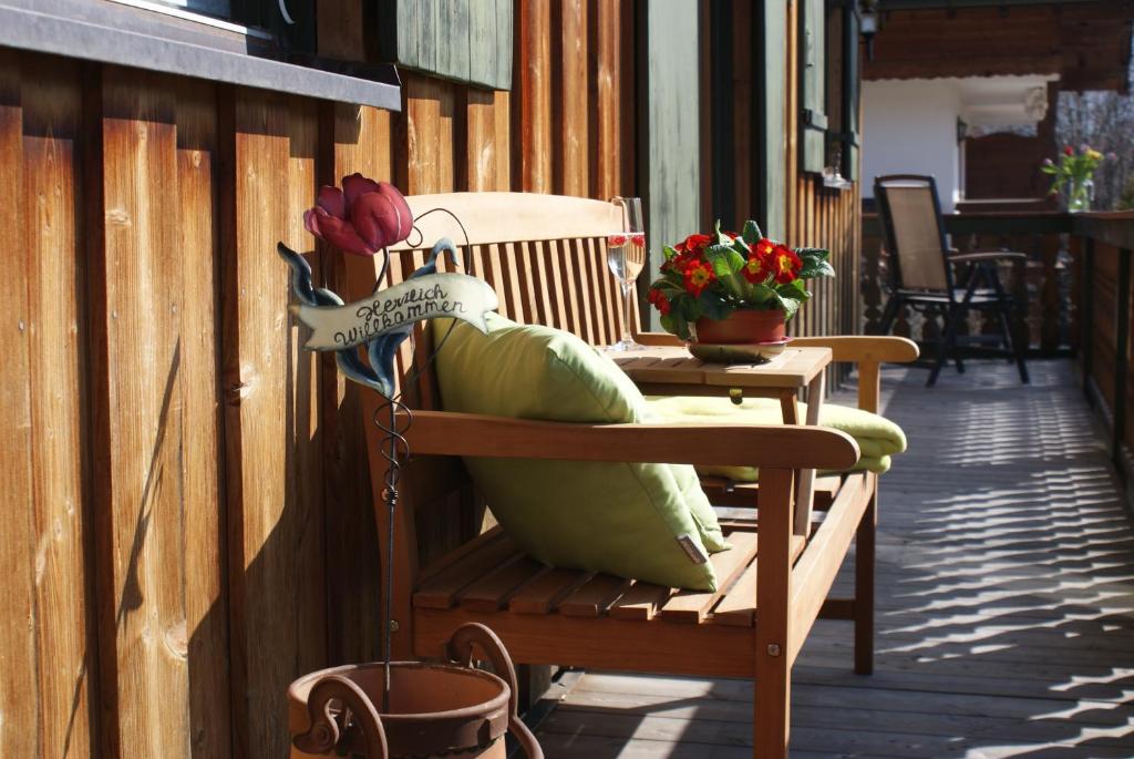 un banco de madera sentado en un porche con flores en Apartment Ape Maja, en Bad Wiessee