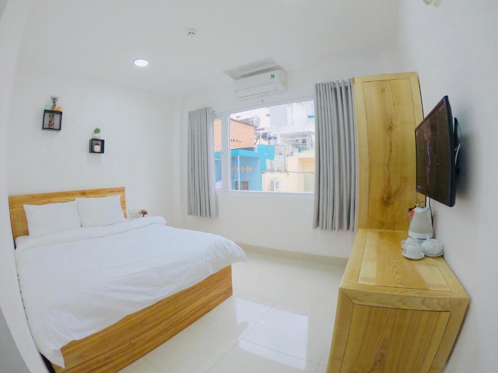 a white bedroom with a bed and a television at Phan Anh Hotel - Bui Vien Walking Street in Ho Chi Minh City