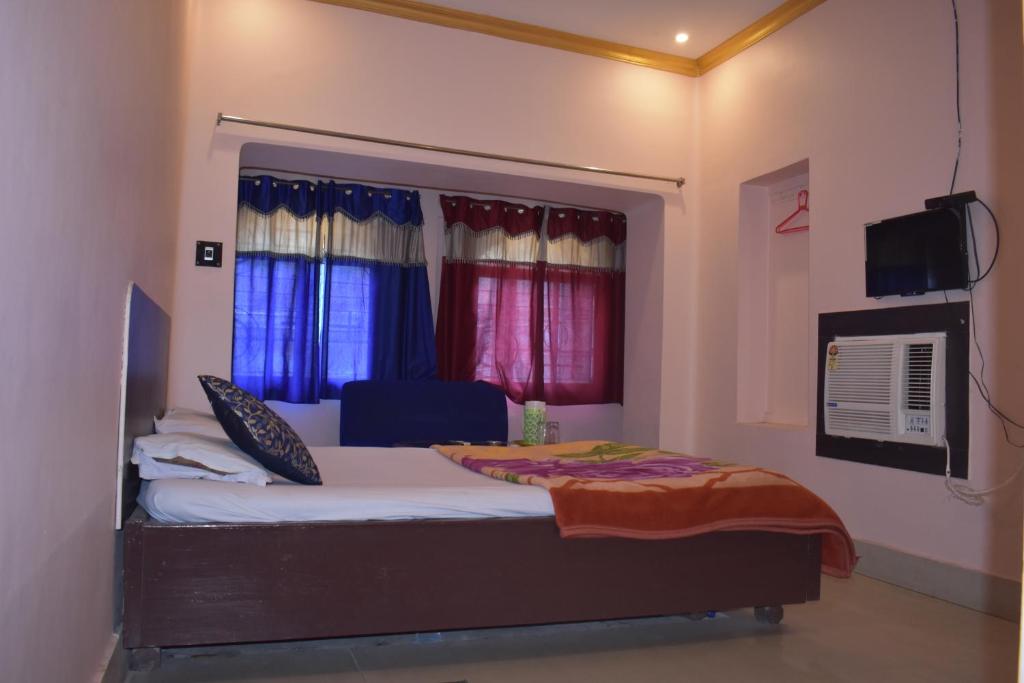 a bedroom with a bed and a tv and windows at Nataraj Hotel and Boarding in Barddhamān