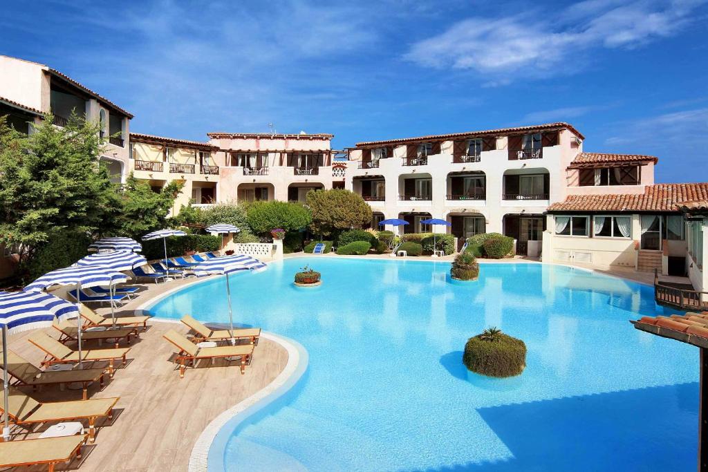 a large swimming pool with chairs and a building at Colonna Park Hotel in Porto Cervo