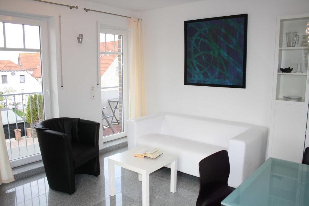 ein Wohnzimmer mit einem weißen Sofa, Stühlen und einem Tisch in der Unterkunft Ferienwohnung Perlmutt in Hooksiel