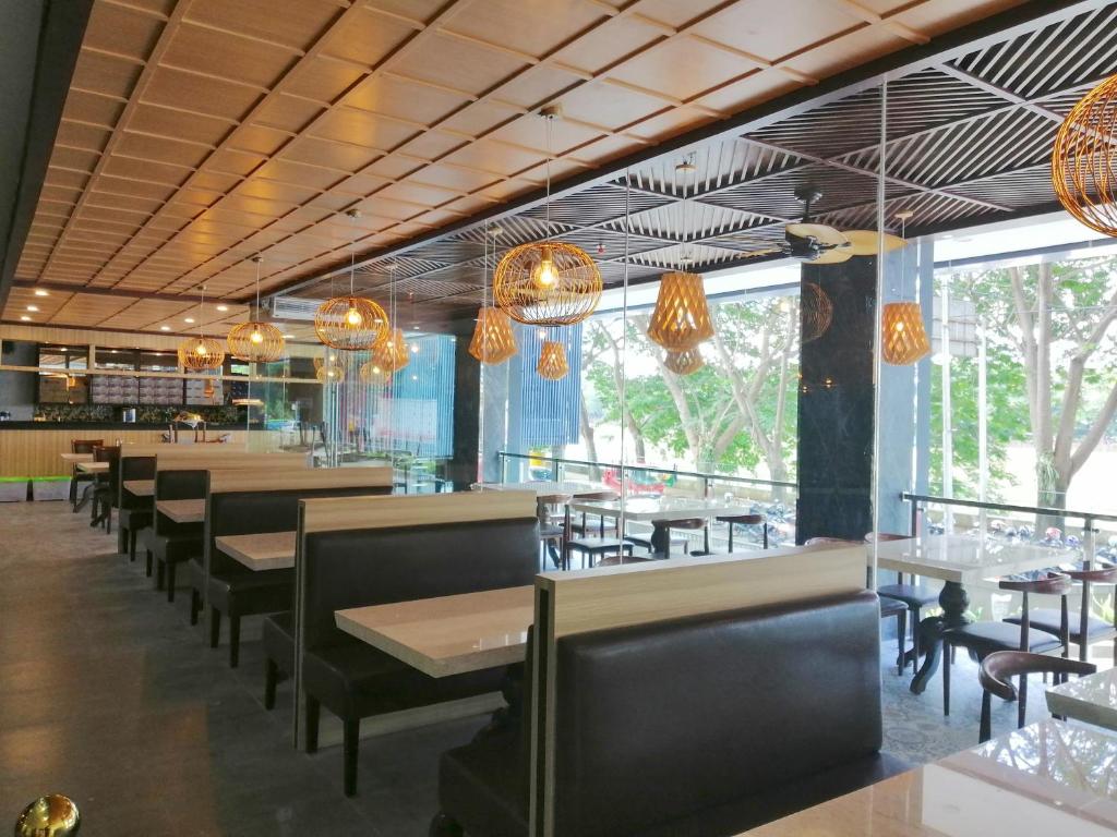 una sala da pranzo con tavoli, sedie e lampadari di Pakons Prime Hotel a Tangerang