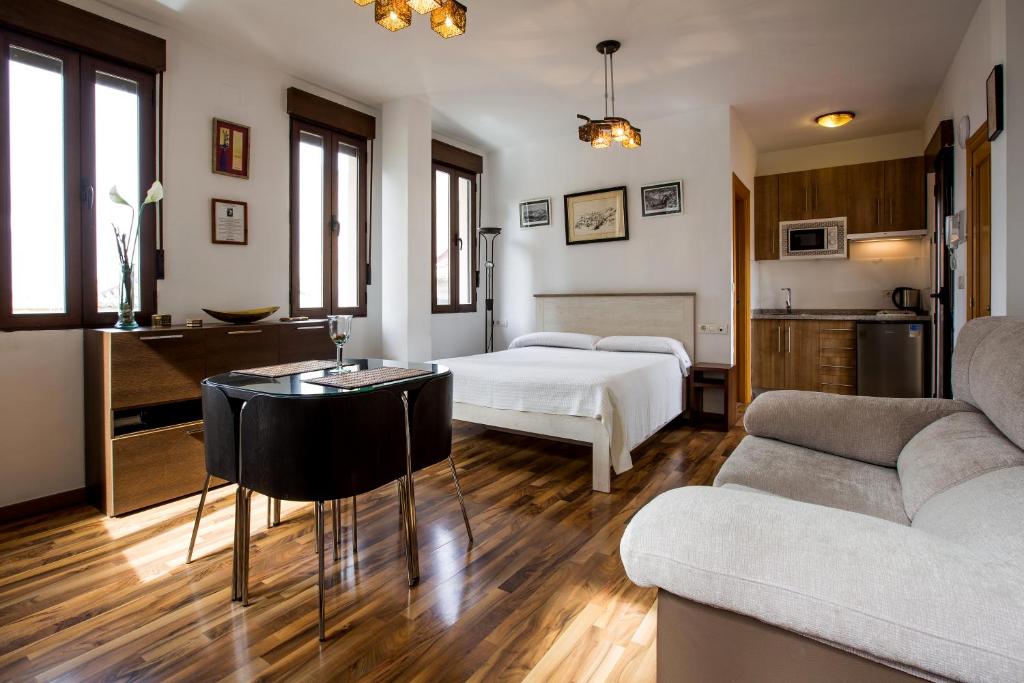 グラナダにあるアパルタメントス カーサ デ ラ ロンハのベッド、テーブル、ソファが備わる客室です。