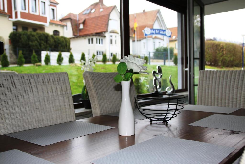 una mesa con un jarrón blanco con flores. en Freizeitcenter Bad Sachsa en Bad Sachsa