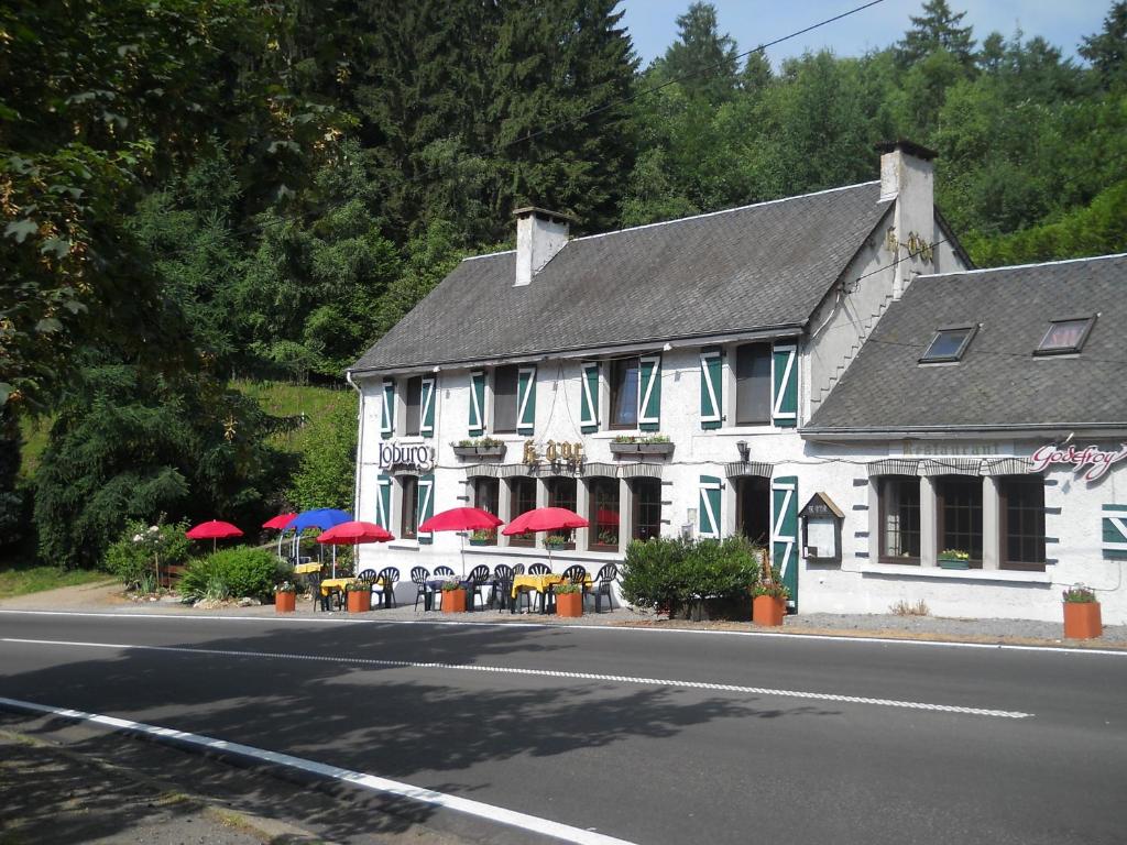 a white building with tables and umbrellas on a street at Le K d'Or in Bouillon