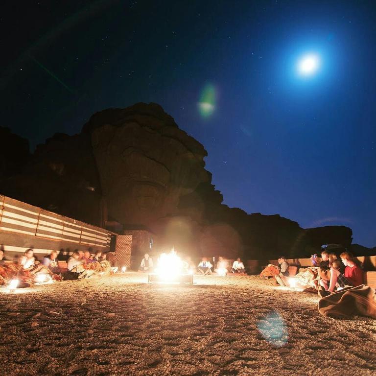 grupa ludzi siedząca wokół ogniska nocą w obiekcie Wadi Rum Excursions w mieście Wadi Rum