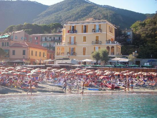 eine Gruppe von Menschen am Strand mit Sonnenschirmen in der Unterkunft Hotel La Spiaggia in Monterosso al Mare