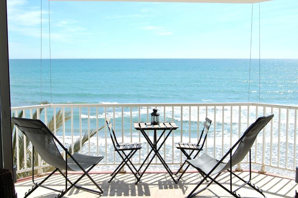 a balcony with chairs and a table and the ocean at SitgesNow Port Alegre Mar in Sitges