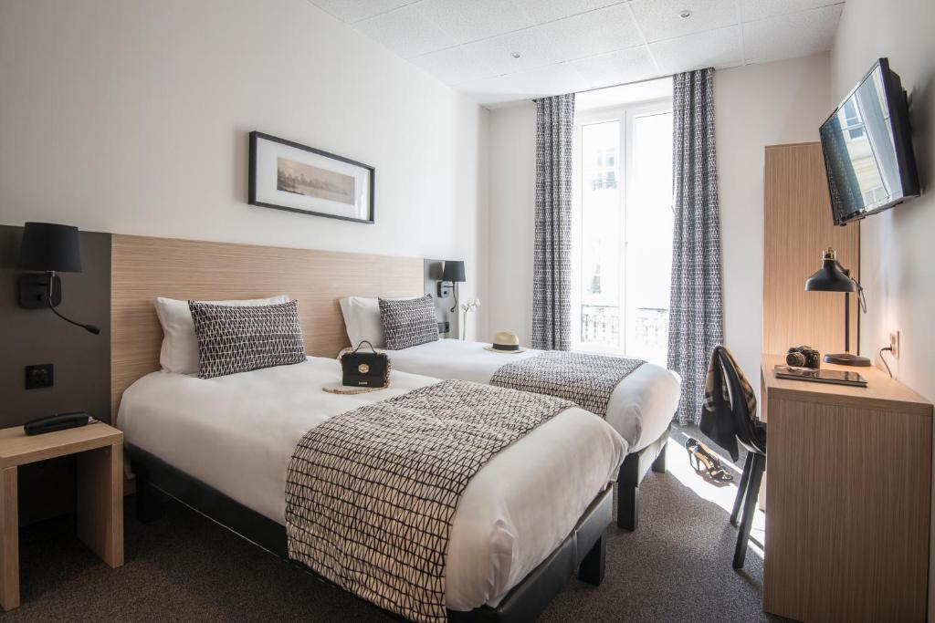 Habitación de hotel con 2 camas y TV en Hotel Saint Gothard en Niza