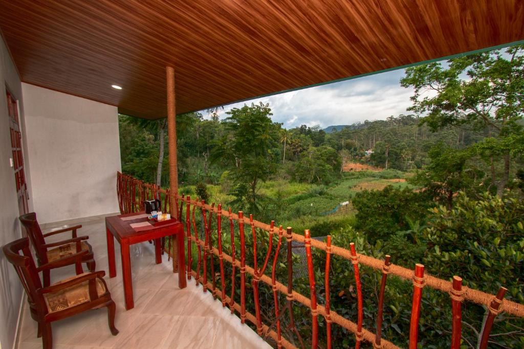 a balcony with a table and a view of a forest at Ella Breeze Homestay in Ella