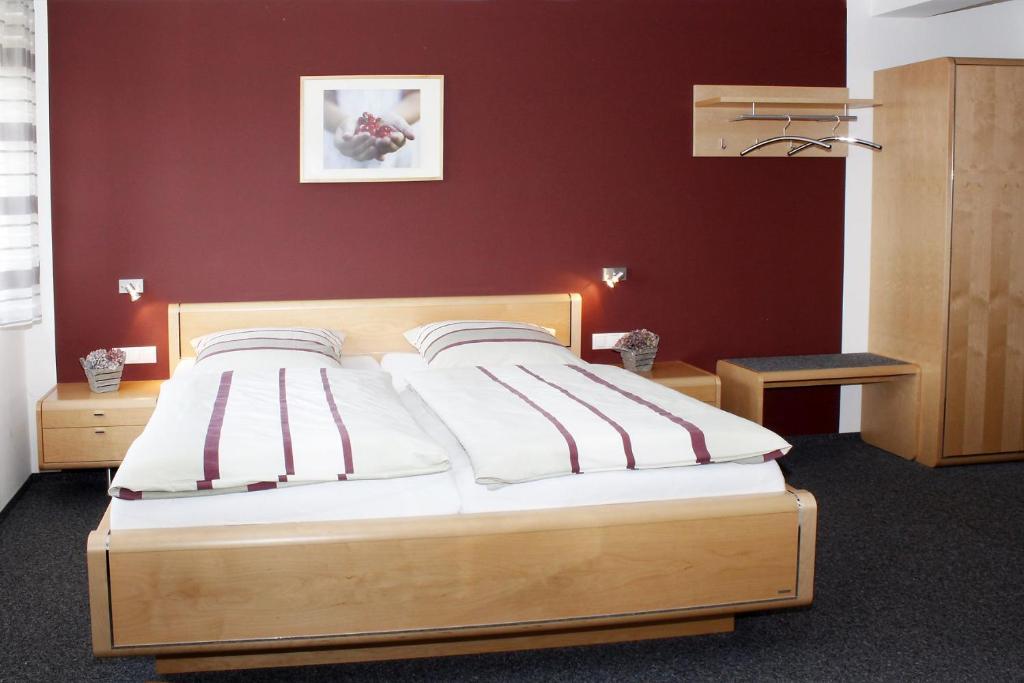 a bed in a bedroom with a red wall at Landgasthaus Badischer Hof in Großrinderfeld