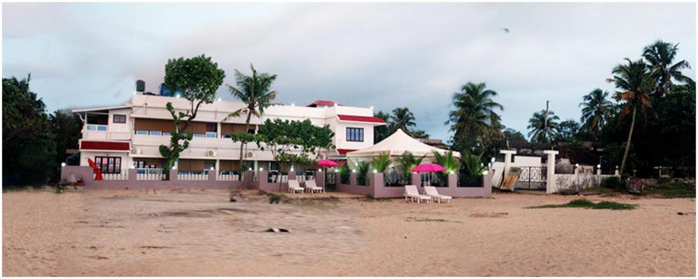 a house on the beach with chairs and umbrellas at Alleppey Holiday Beach Resort in Alleppey