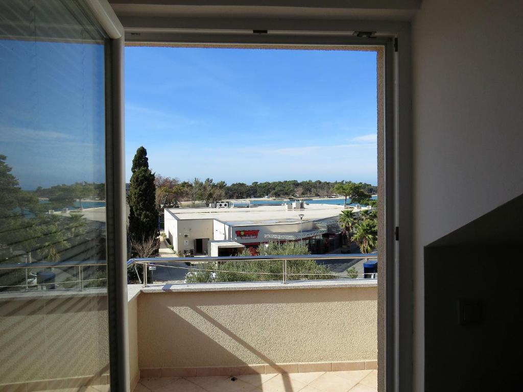 an open door to a balcony with a view of a building at Apartments Karolina in Novalja