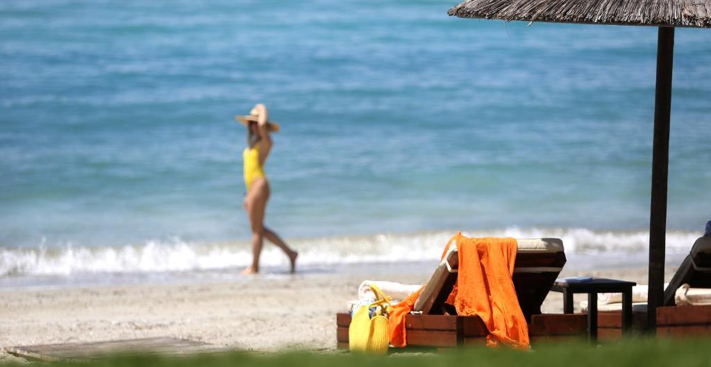 a woman in a yellow bikini walking on the beach at Olympion Sunset Halkidiki in Fourka