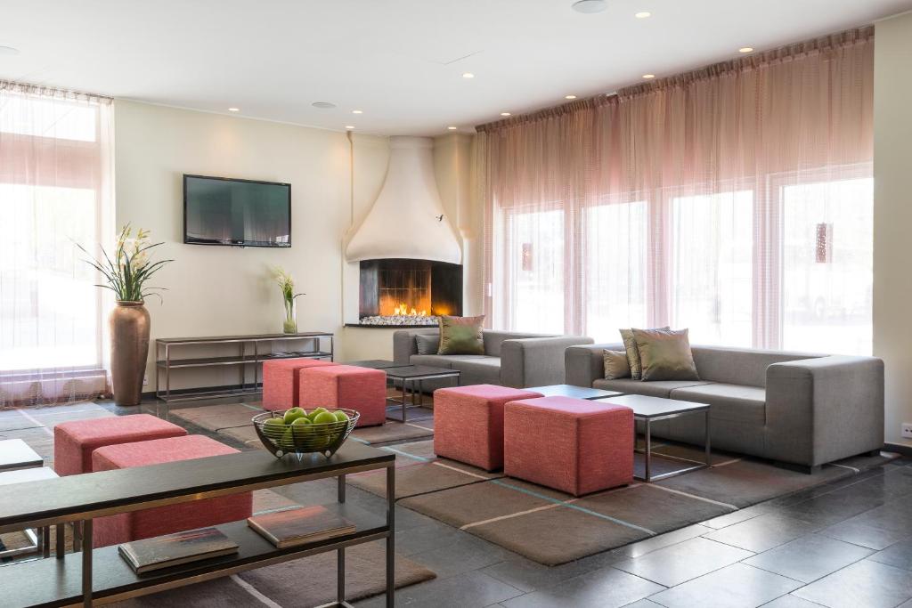 a living room with couches and tables and a fireplace at Quality Hotel Luleå in Luleå