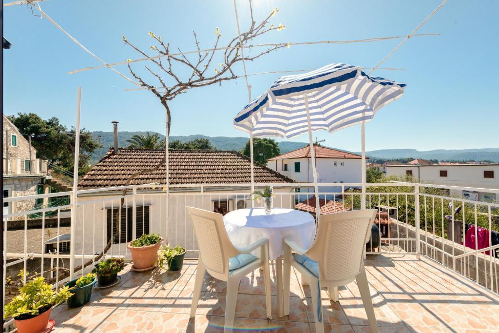 a table and chairs on a balcony with an umbrella at Apartment Anic in Stari Grad