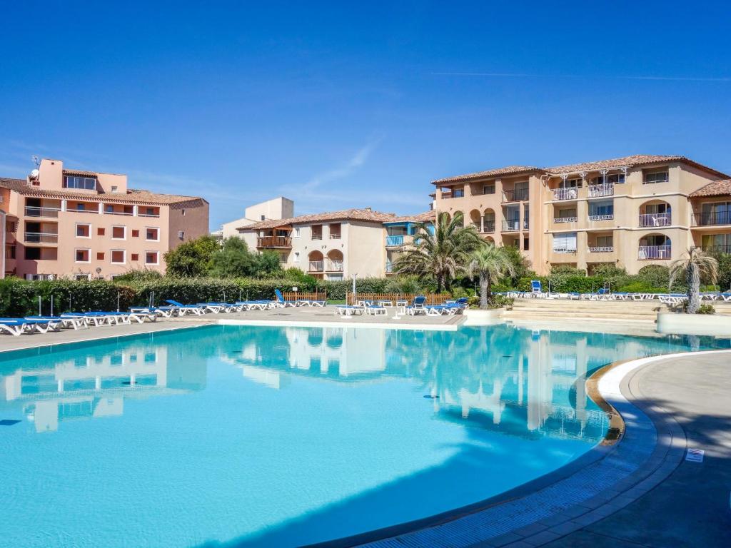 une piscine avec des chaises et des bâtiments en arrière-plan dans l'établissement Apartment Les Rivages de Coudoulière-2 by Interhome, à Six-Fours-les-Plages