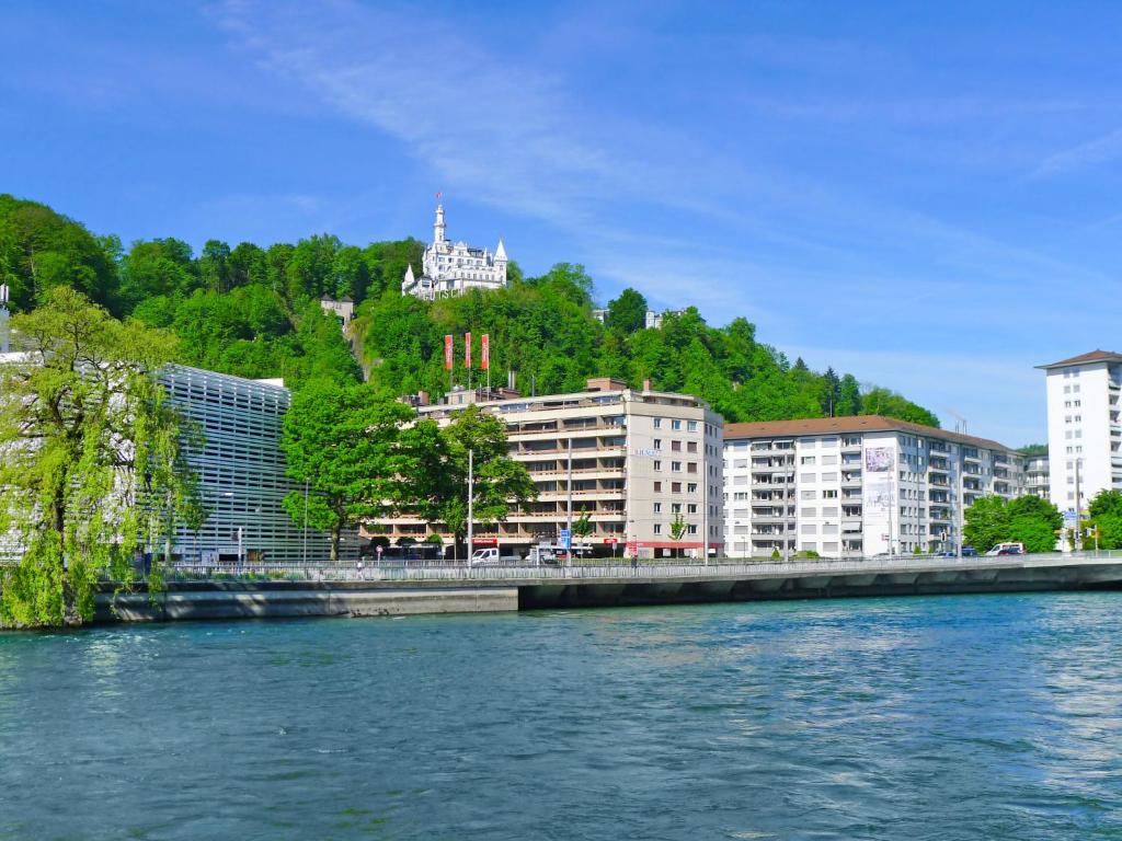 een waterlichaam met gebouwen op een heuvel bij Apartment BHMS City Campus by Interhome in Luzern