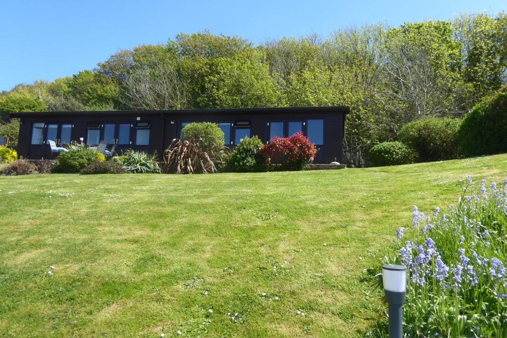a black house on a hill with a yard at Pebble Lodges in Gurnard