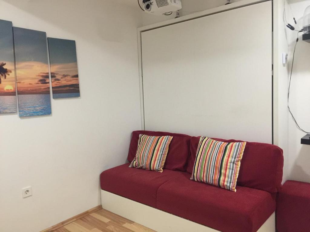 un sofá rojo sentado en una habitación con pinturas en Apartment Red Square, en Liubliana