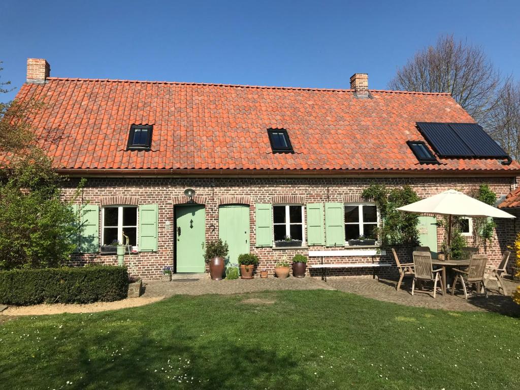 een huis met een oranje dak met een tafel en stoelen bij Den Haegepreeck in Horebeke