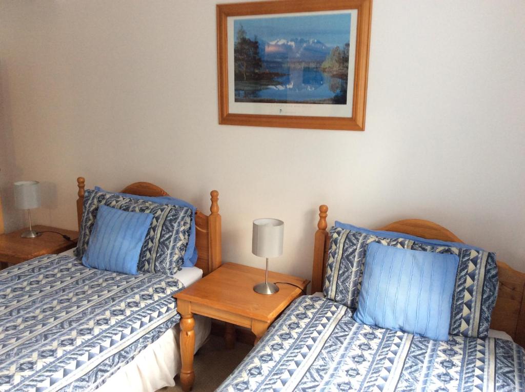 1 dormitorio con 2 camas y una foto en la pared en Dalkell Cottage, en Tyndrum